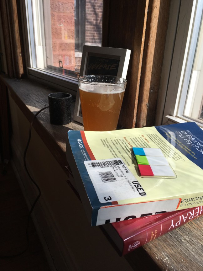 Photo of a stack of book, some plants, and a beer on a window sill 